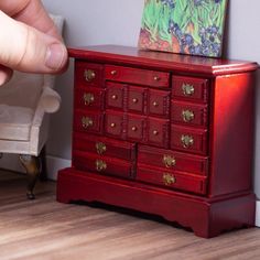 a hand is pointing at a red dresser