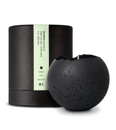 a black vase sitting on top of a table next to a container with a label