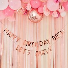 a birthday party with balloons and streamers on the wall, pink curtains and tassels