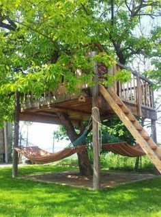 a tree house with a hammock in the yard