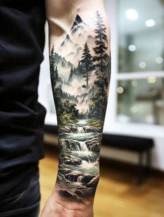 a man's arm with a mountain scene on it and trees in the background