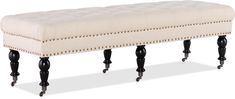 an upholstered bench with black legs and buttons on the back is shown against a white background