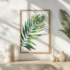 a green leaf is hanging on the wall next to two vases and a plant