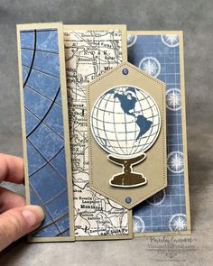 a hand is holding up a card with a globe on the front and blue background