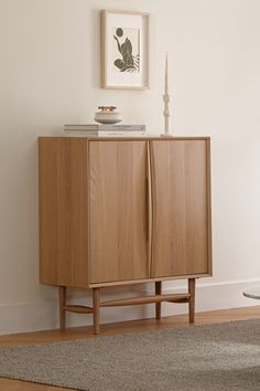 a wooden cabinet sitting on top of a hard wood floor next to a white wall