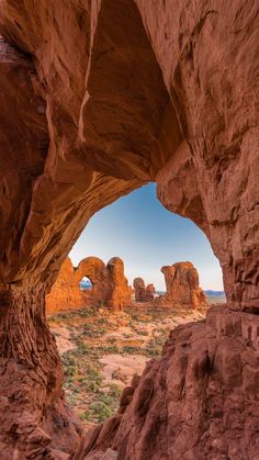 an arch in the desert with rocks and grass around it, viewed from inside one