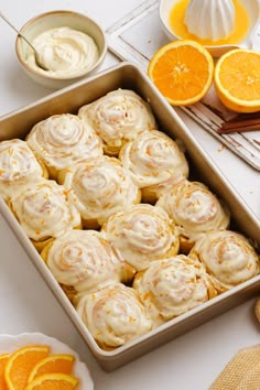 a pan filled with orange meringue rolls next to sliced oranges