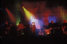 a group of people that are on stage with some lights in the dark behind them