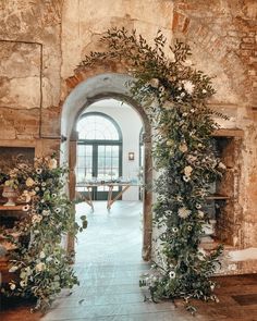 an arched doorway with flowers and greenery on the outside, leading to a dining room