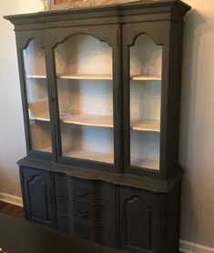 a black china cabinet with glass doors and shelves