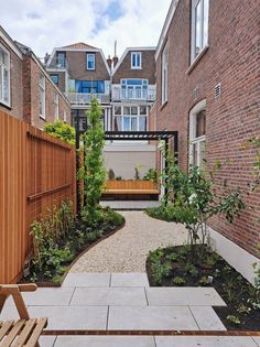 an outdoor courtyard with wooden benches and plants in the foreground, surrounded by brick buildings