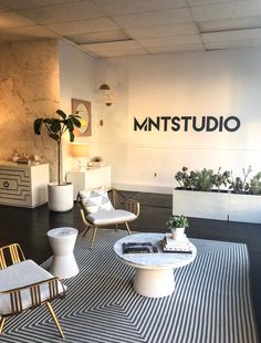 an office with chairs, tables and plants on the floor in front of a sign that reads mttstudio