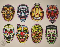 a group of halloween masks painted on the side of a white wall with different colors