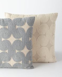 two decorative pillows sitting next to each other on a white surface, one with blue and beige circles