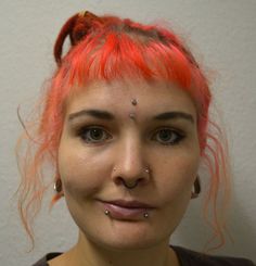 a woman with red hair and piercings on her nose