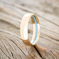 a close up of a wedding ring on top of a piece of wood with blue inlays