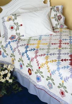 a white bed sitting next to a vase with flowers on it