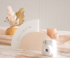 a white camera sitting on top of a wooden table next to a vase with flowers