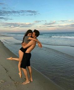 a man and woman hugging on the beach