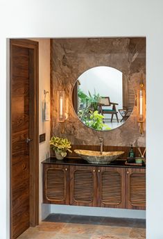 a bathroom with a round mirror above the sink and wooden cabinetry on the wall