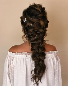 a woman with long hair wearing a white blouse and braid in her hair, looking off to the side