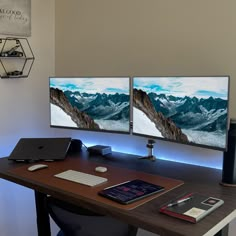 two computer monitors sitting on top of a wooden desk