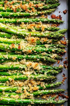 cooked asparagus with parmesan cheese and seasonings on a baking sheet