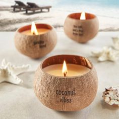 three coconut candles sitting on top of a sandy beach