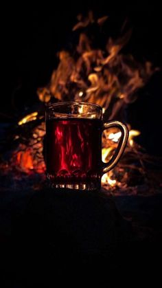 a cup of tea sitting on top of a table in front of a fire pit