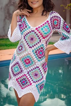 a woman standing next to a pool wearing a crocheted dress