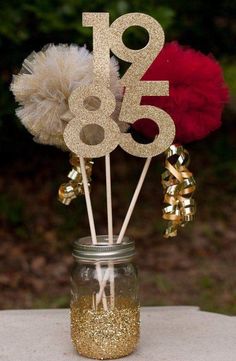 a mason jar filled with gold glitter and red pom - poms sitting on top of a table