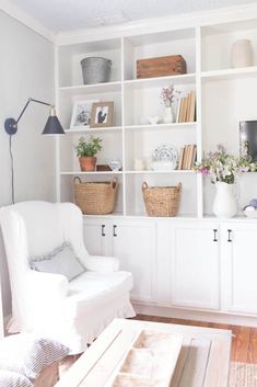 a living room filled with white furniture and lots of bookshelves on top of it