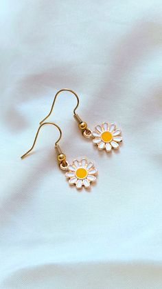 Add a touch of whimsy to your outfit with our Daisy Earrings. These adorable daisies will bring a smile to your face and brighten up any look. Perfect for adding a playful touch to your style. 🌼 Earring Details: White daisies Gold furnishings Cute Gold Jewelry For Spring, Playful White Dangle Jewelry, Trendy Daisy-shaped Spring Jewelry, Cute Flower Shaped Jewelry With Matching Earrings, Playful White Jewelry With Ear Wire, Cute Spring Drop Earrings, Trendy Nickel Free Flower Shaped Earrings, Trendy Handmade Daisy Jewelry, Whimsical Spring Earrings With Flower Charm