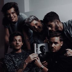 the group of men are posing together for a photo with one holding a book in front of them