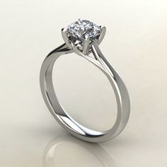 a white gold engagement ring with a round brilliant diamond in the center, on a plain surface