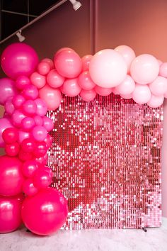 pink and white balloons in front of a backdrop with sequins