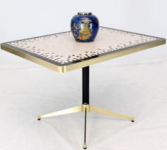 a blue and white vase sitting on top of a metal table with gold trimmings