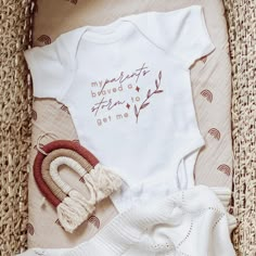 a baby's bodysuit, hat and booties are laying on a wicker mat