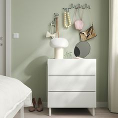 a white dresser sitting next to a bed in a bedroom