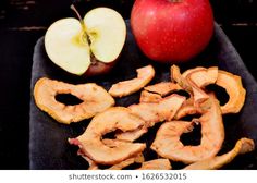 an apple and some sliced up apples on a black plate with the peels removed