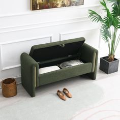 a green couch sitting on top of a white floor next to a potted plant