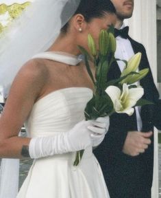 a man and woman in wedding attire standing next to each other with flowers on their hands