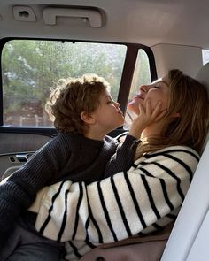 two people sitting in the back seat of a car, one is kissing the other