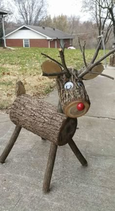 a wooden reindeer with red nose and antlers on it's head is standing in front of a house