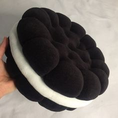 a hand holding a black and white round cushion