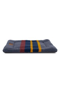 a dog bed that is blue and yellow with stripes on the front, sitting on a white background