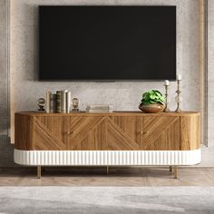 a tv mounted on the wall above a wooden cabinet with plants and candles in front of it