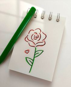 a drawing of a rose on a piece of paper next to a green marker pen