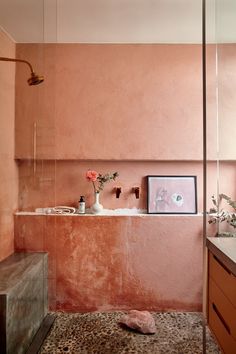 a bathroom with pink walls and leopard print flooring is pictured in this image, there are two vases on the counter next to the tub