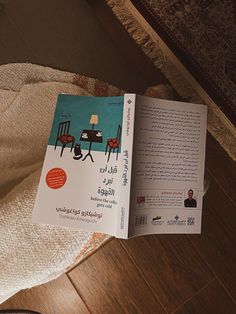 an open book sitting on top of a wooden floor next to a chair and table